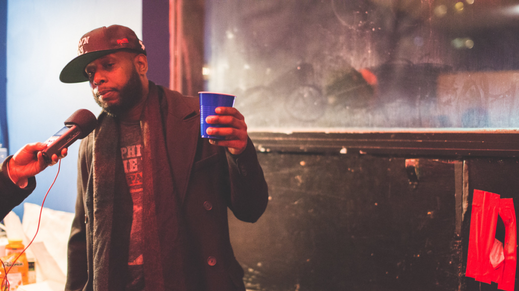 Talib Kweli holding mic and cup