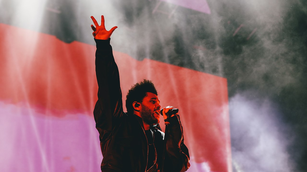 The Weeknd performing with raised arms