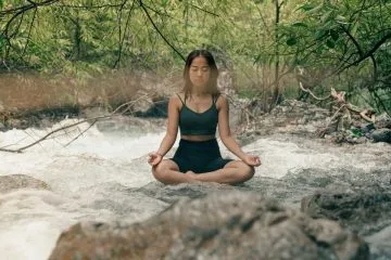 Woman meditates among trees