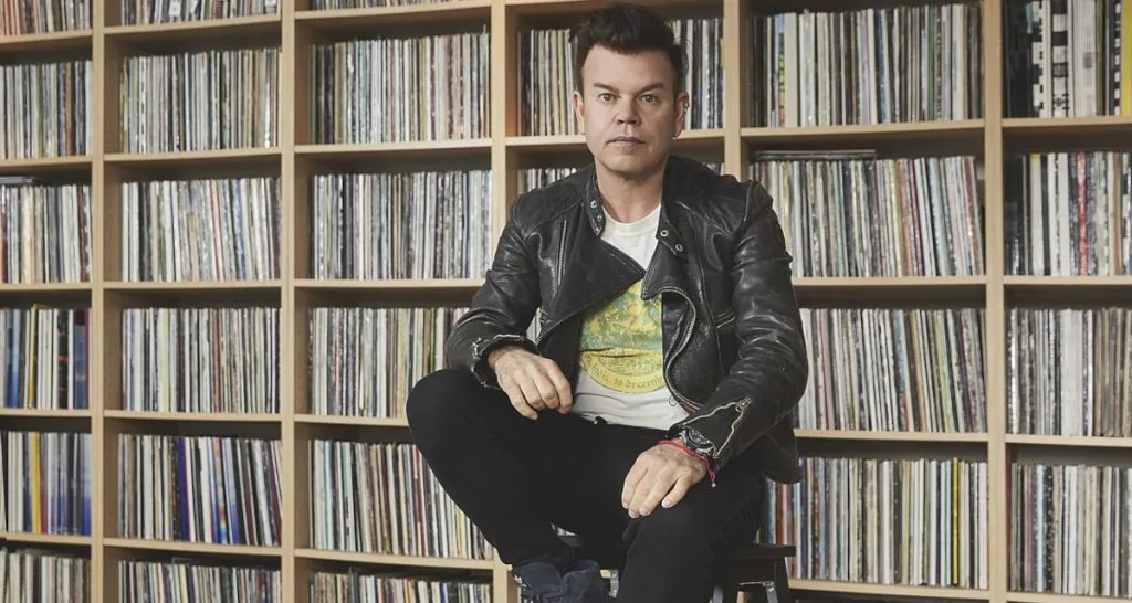 Paul Oakenfold seated by bookshelf